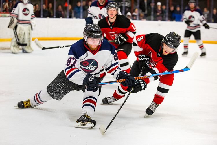 Two hockey players battle for the puck