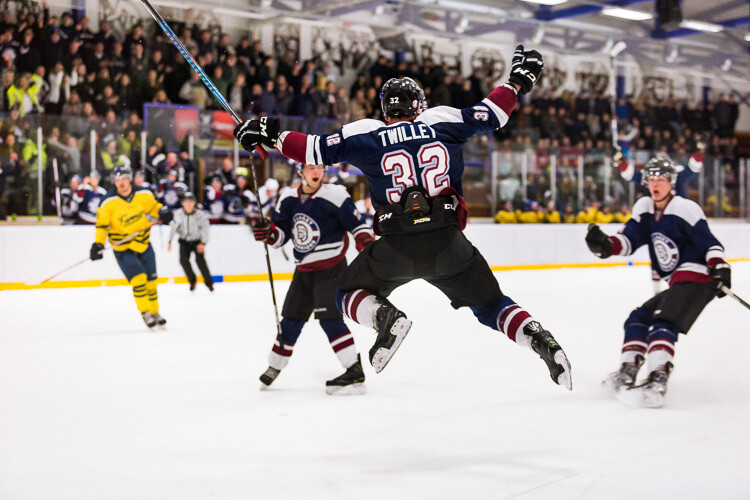 A hockey player jumping into the air in celebration after scoring the winning goal - Tips for Editing Hockey Photos in Lightroom