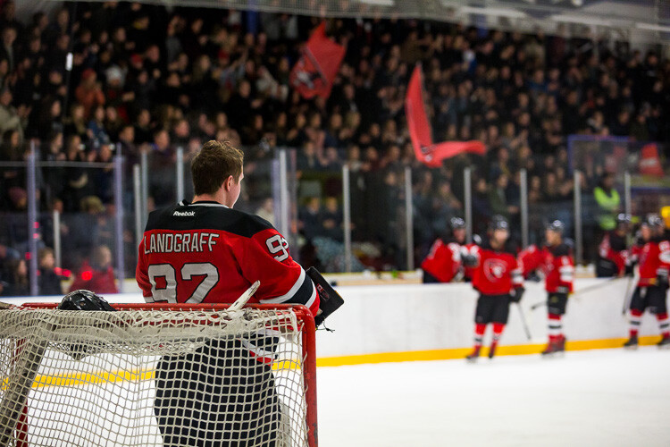 A hockey goaltender taking a break while the crowd cheers - Tips for Editing Hockey Photos in Lightroom